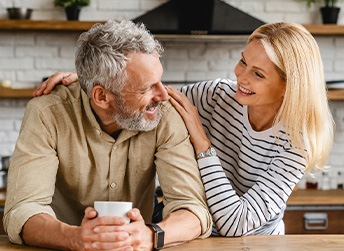 Man and woman leaning on wood surface smiling at each other