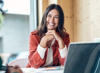 Woman in red jacket at work table with laptop