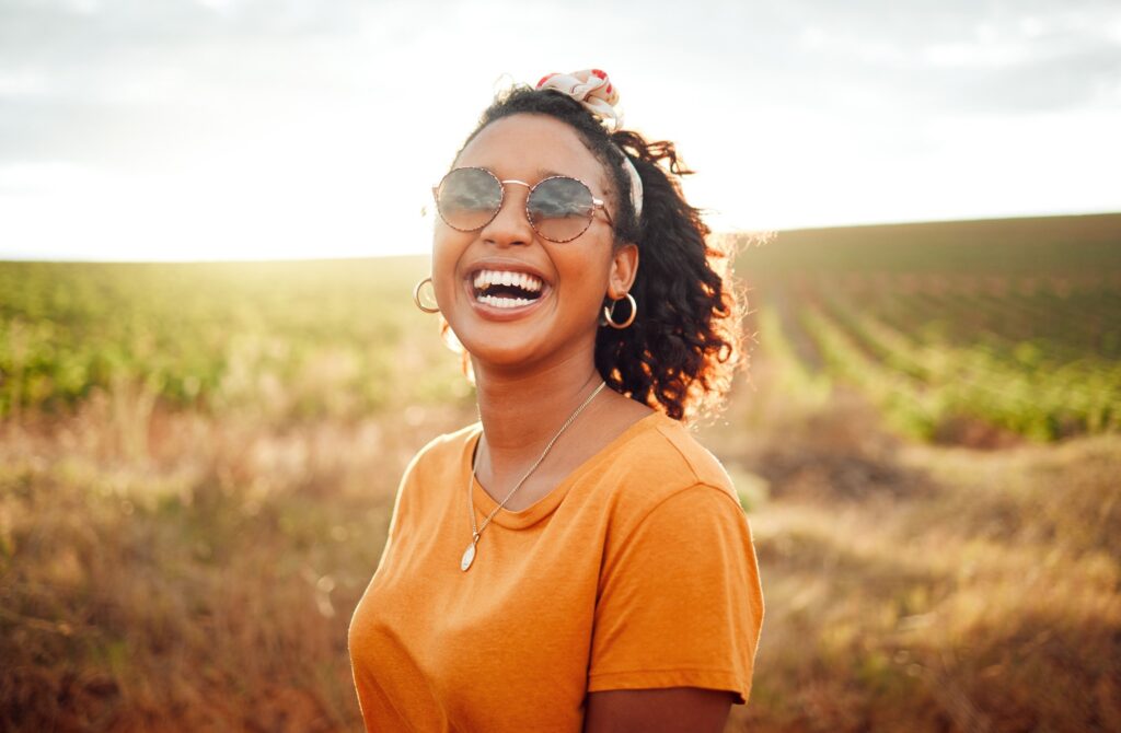 Woman in orange shirt smiling outside in a field